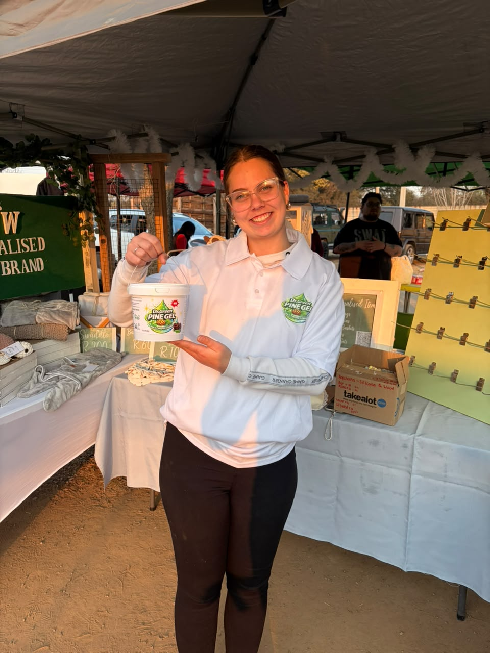 Vendor holding a Dr Green Pine Gel tub at a market stall
